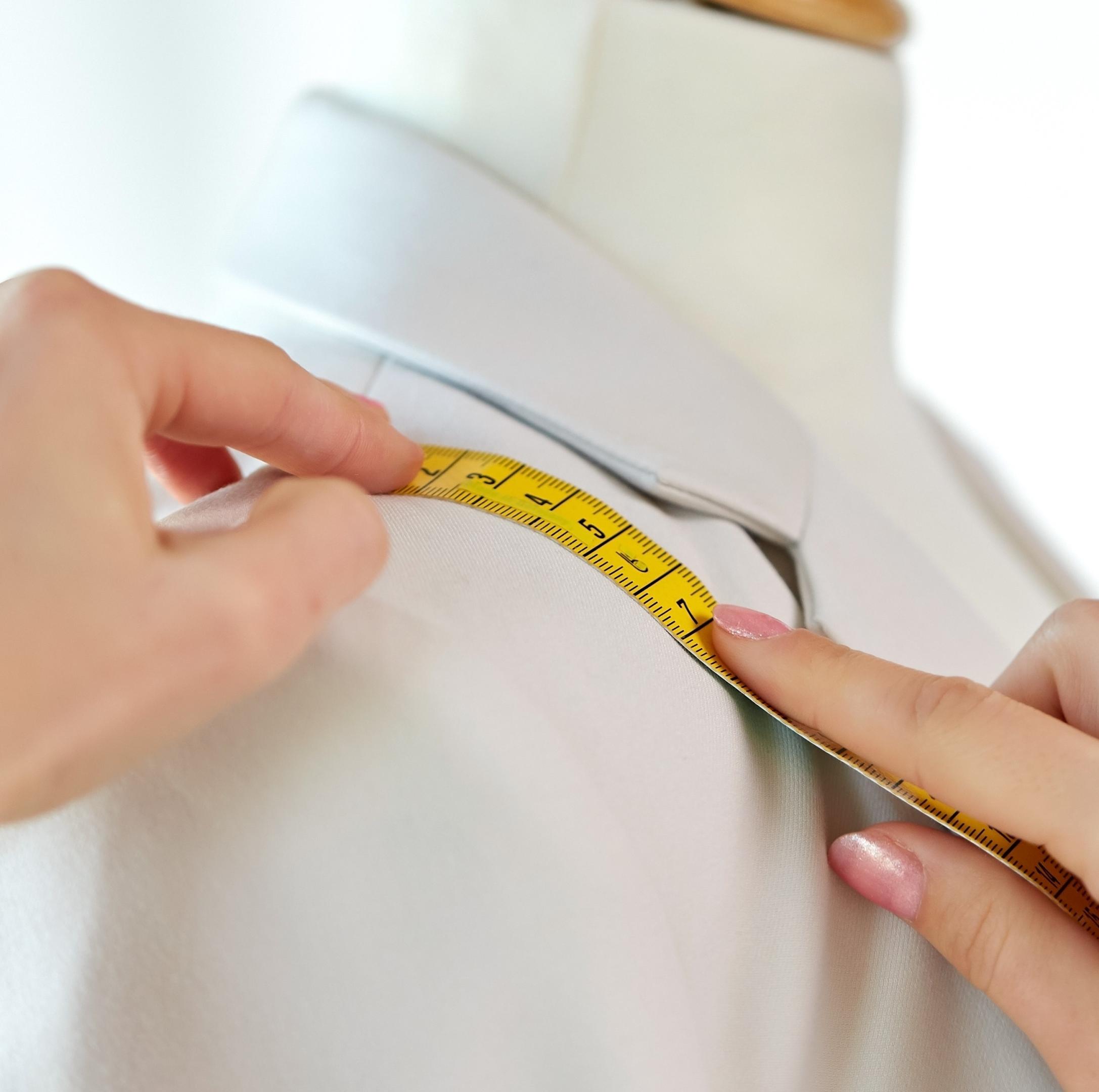 fashion designer measures jacket with tape measure